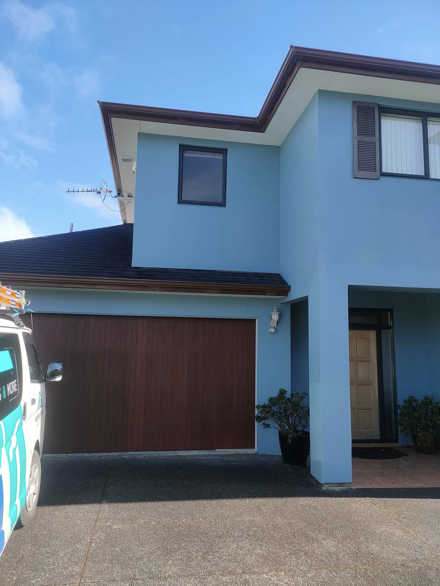 Blue two-storey Auckland home exterior with a Second to None vehicle outside