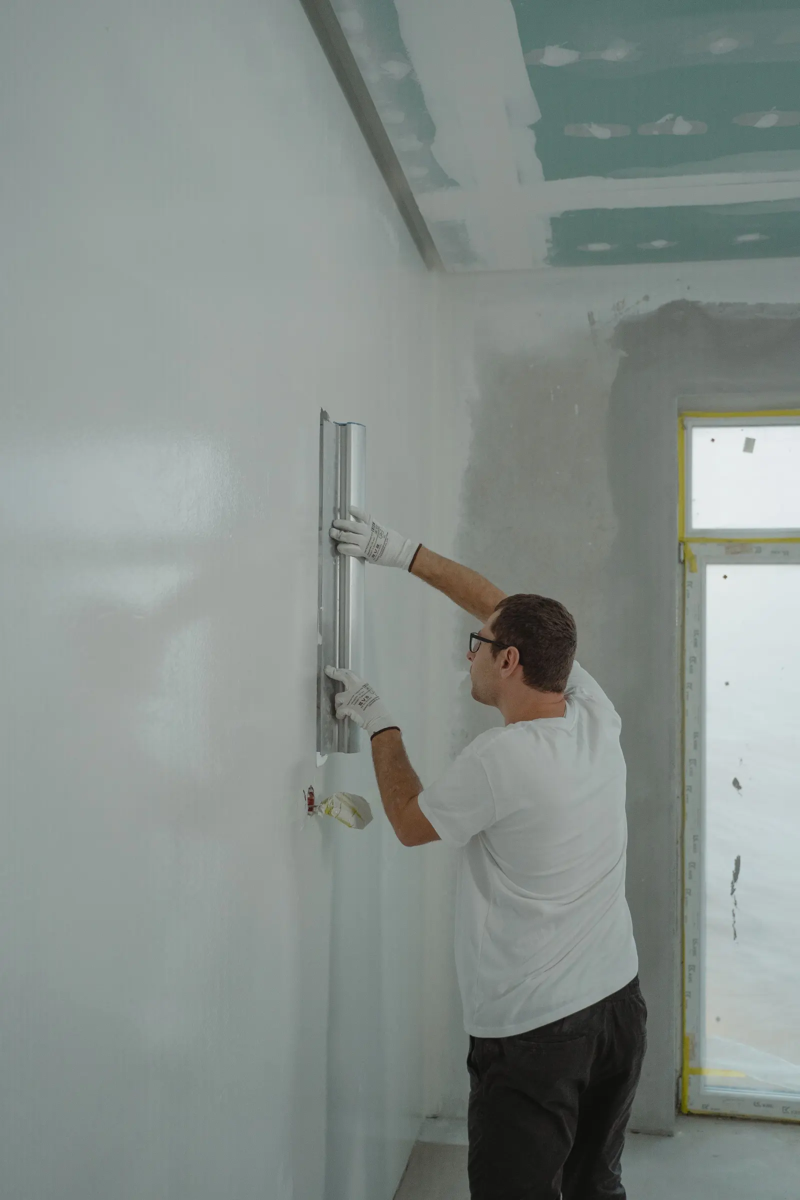 Painter rolling a wall in a protected interior room