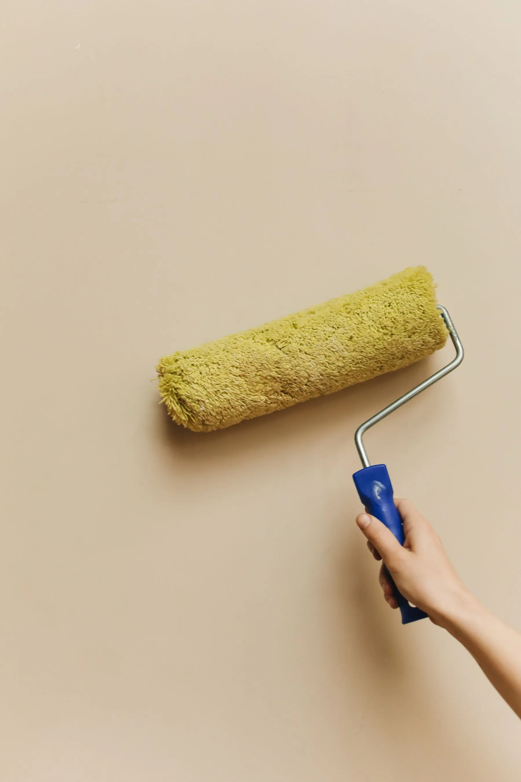 Paint roller moving across a neutral interior wall