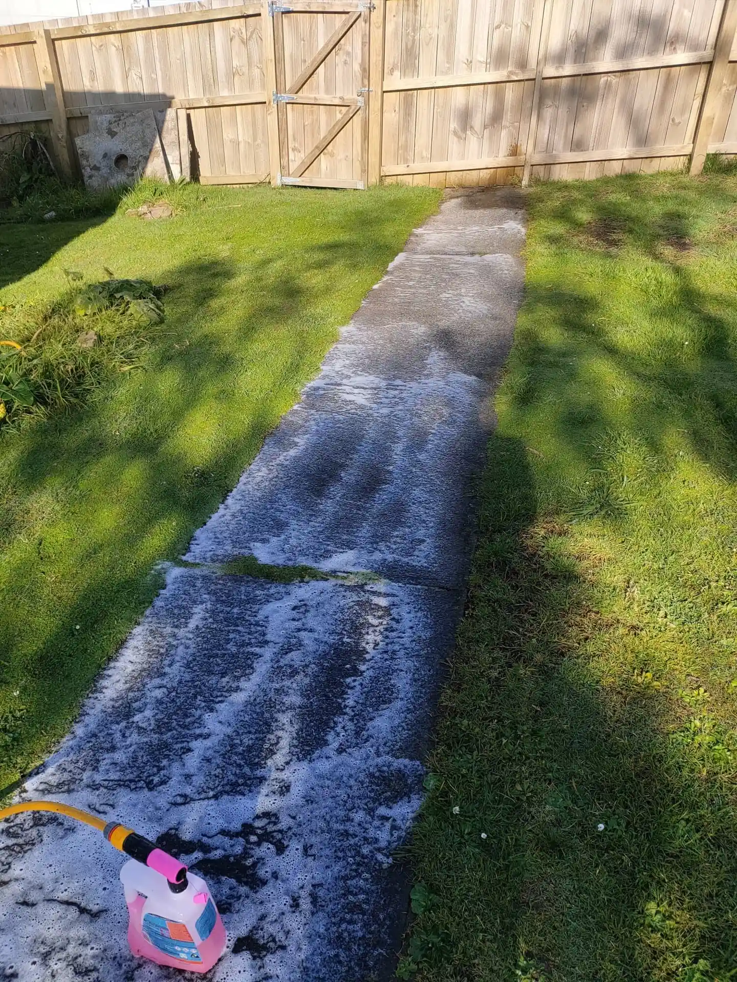 Concrete path partway through a pressure wash, half clean and half still soiled